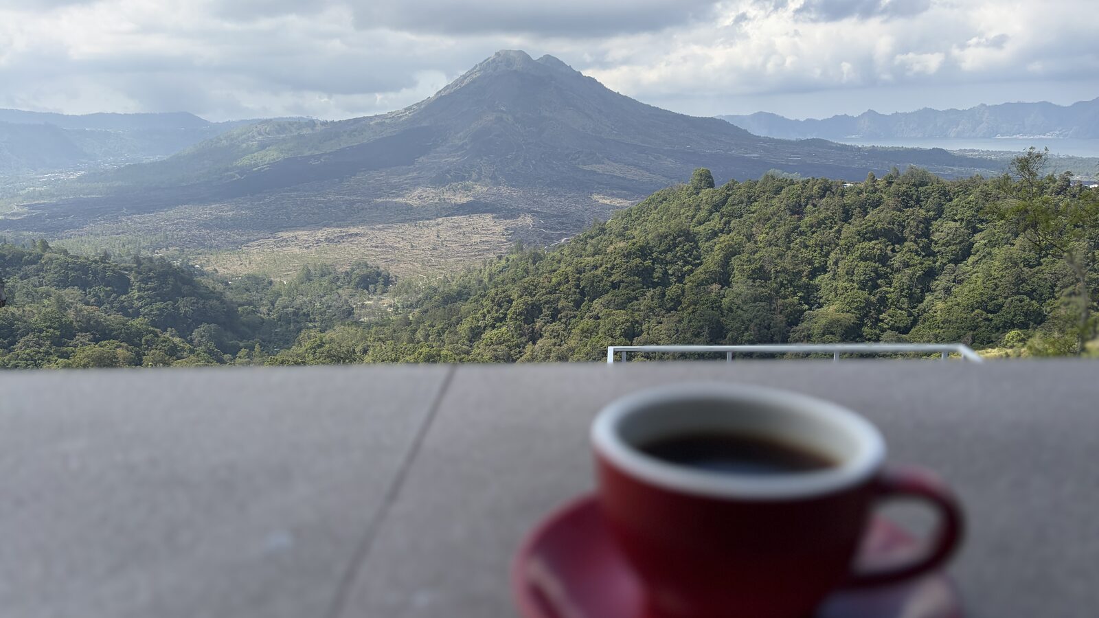 バトゥール山を背にテーブルに置かれた、赤いカップのコーヒー